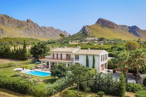 A two-story house with a swimming pool, surrounded by lush greenery and mountains. - Villa Can Dala luxury in Port de Pollensa Sleeps 12 (Puerto Pollensa)