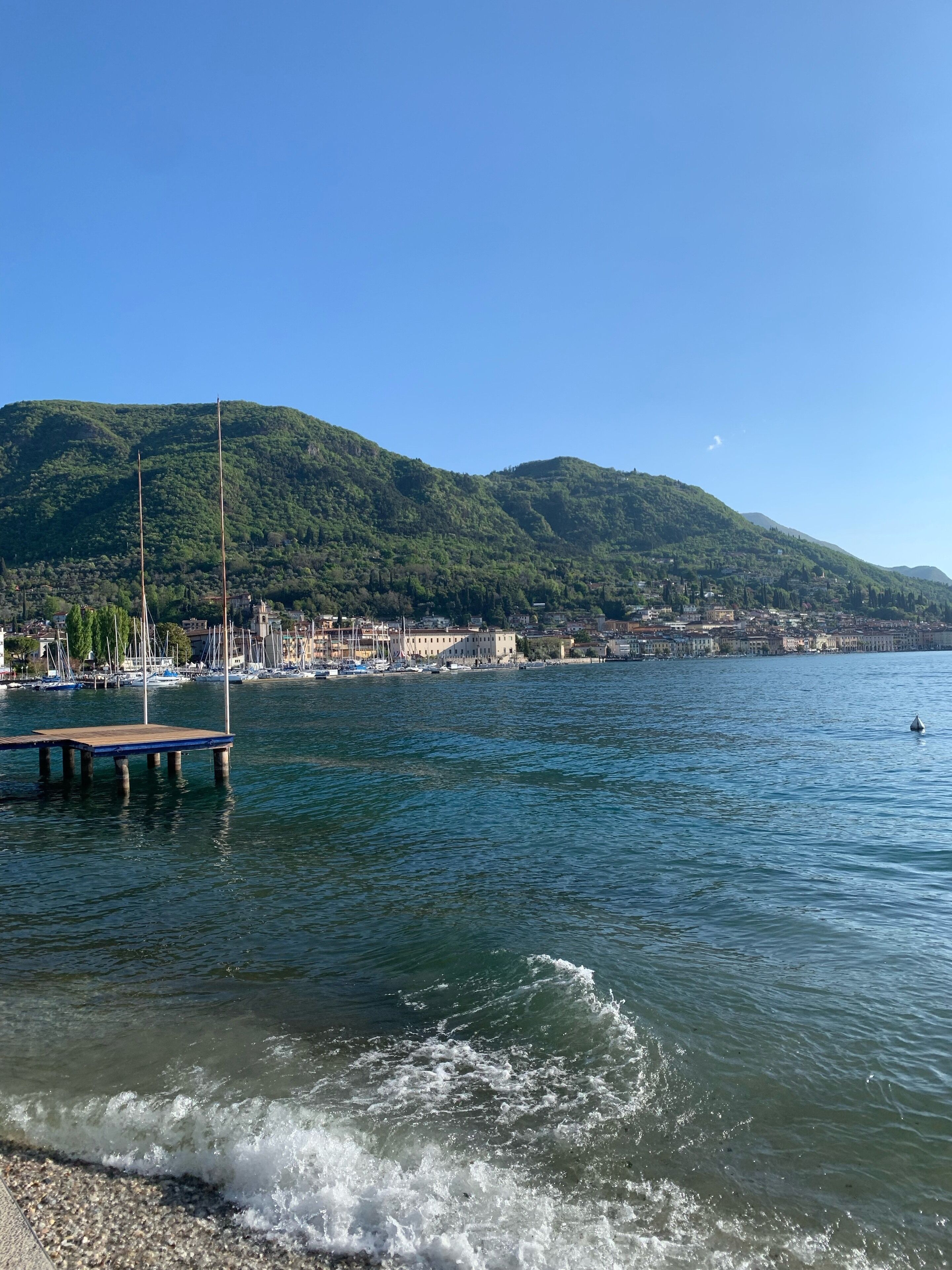 A waterfront view with a dock, calm water, and a backdrop of green hills.
