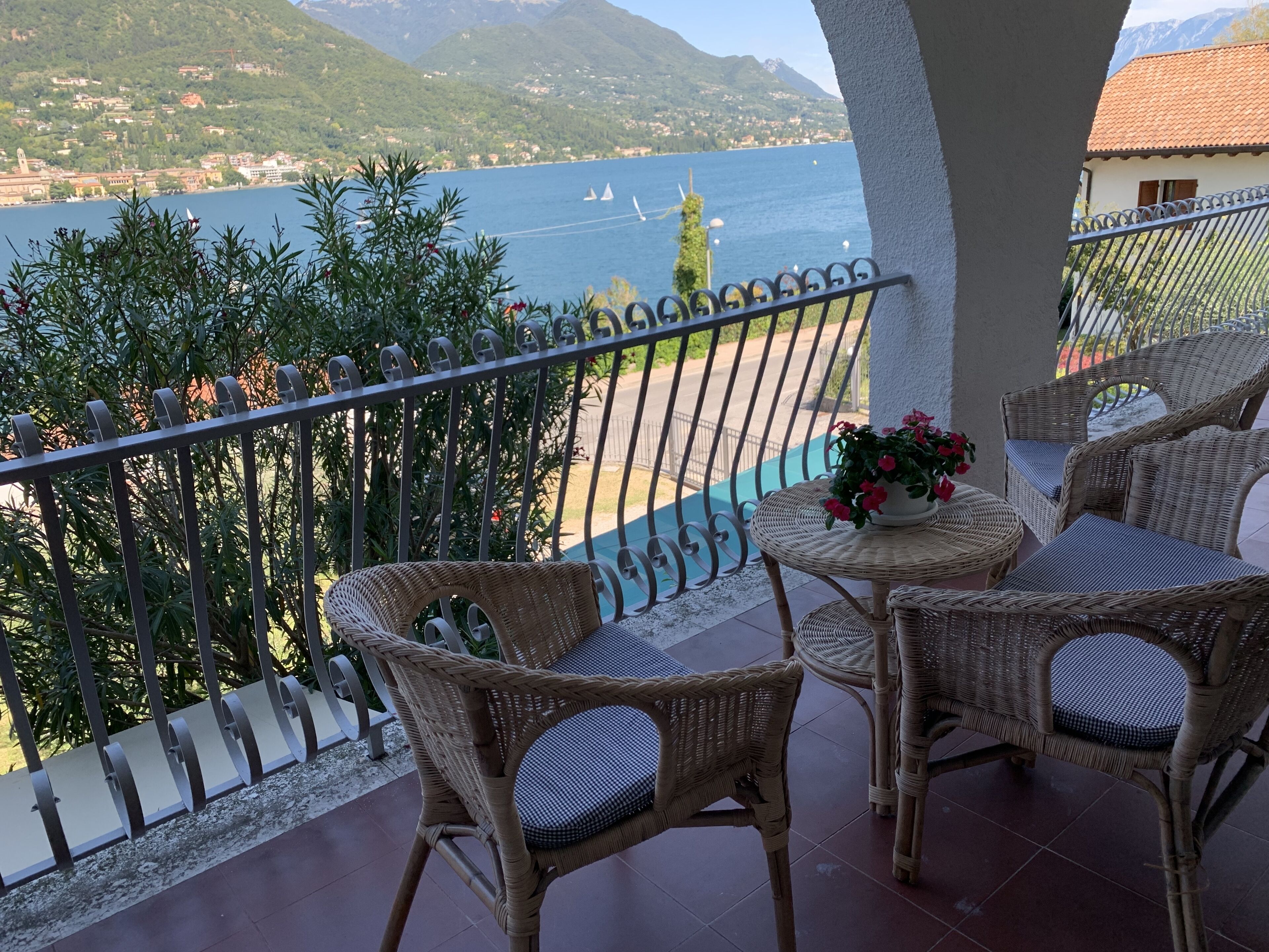 A balcony with wicker furniture and a view of a lake and mountains.