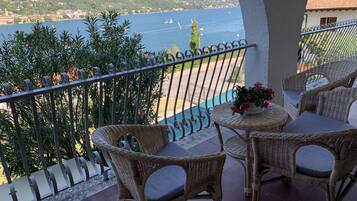 A balcony with wicker furniture and a view of a lake and mountains.