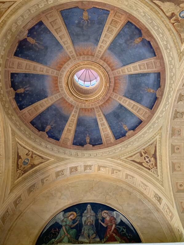 Un plafond somptueux et richement décoré, doté d’une grande ouverture circulaire au centre et d’une fresque détaillée en dessous.
