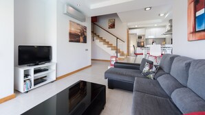 Ein modernes Wohnzimmer mit Flachbildfernseher, grauem Sofa und Couchtisch.