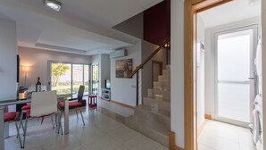 Ein modernes Wohnzimmer mit Essbereich, einer Treppe und Blick ins Freie.