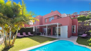 Ein modernes Haus mit Swimmingpool, überdachter Terrasse und gepflegtem Rasen.