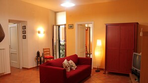 A living room with a red sofa, a television, and a lamp. - Naples 28 Holiday Home (Napoli)
