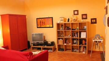A living room with a red sofa, a television, a bookshelf, and a wooden cabinet.