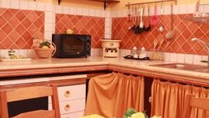 A kitchen with a yellow table set for dining, a microwave, and various kitchen utensils on the wall. - Naples 28 Holiday Home (Napoli)