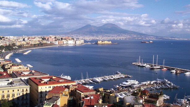 A coastal cityscape with a marina, buildings, and a mountain in the background. - Naples 28 Holiday Home (Napoli)