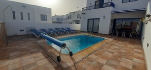 Ein Swimmingpool mit blauen Liegestühlen, einer Wasserrutsche und einer gefliesten Terrasse.