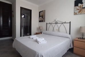 Ein Hotelzimmer mit Bett, Nachttisch, Lampe, Tür und Dusche.