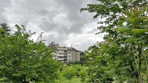 A gravel path leading to a building with multiple balconies, surrounded by lush greenery and a cloudy sky. - Relaxation in Rome away from the chaos - balcony, light and easy parking (Roma , Monte Sacro)