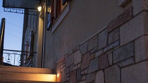 Eine Treppe mit Steinwänden und einem Metallgeländer, die zu einer Tür mit Glasfenster führt.