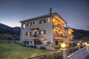 A two-story house with a stone facade, multiple balconies, and a well-lit entrance. - Luxury  Villa, panoramic sea view, peaceful surroundings, near Nafpaktos city (Ano Platanitis Nafpaktos)