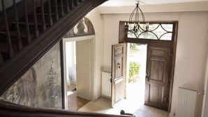 Una escalera que lleva a un cuarto con una araña, una puerta de madera y vistas al exterior.