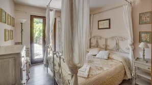Ein Schlafzimmer mit einem Himmelbett, einem Nachttisch, einer Kommode und einer Tür, die auf einen Balkon führt.