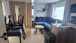 A modern kitchen with wooden cabinets, a dining table, and a seating area with a sofa and a small round table. - Mobile home 6 sleeps 4 * Domaine in the heart of the Loire Valley Castles  (Veuzain-Sur-Loire)