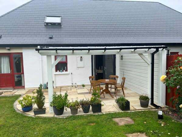 A house with a covered patio, a red door, and a garden with potted plants. - #Charming Killarney Cottage (Aghadoe)