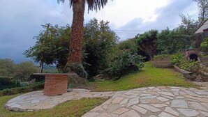 A stone pathway leading to a brick structure surrounded by lush greenery and a palm tree. - Oruna De Pielagos: Country Cottage / Gite - Santander (Oruña de Piélagos)