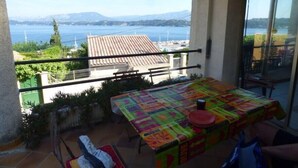 Un balcó amb taula preparada per dinar, amb vista panoràmica d'un llac i muntanyes.