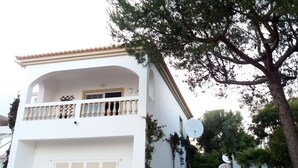 Um edifício branco com varanda, garagem e antena parabólica.