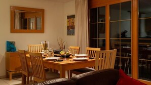 A dining area with a wooden table set for four, surrounded by chairs. - Beautiful apartment with balcony and waterfall view (Lauterbrunnen)