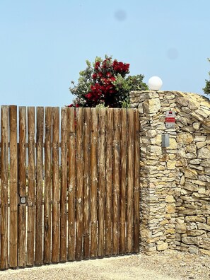 A wooden fence, a stone wall, and a red flowering bush. - Sunset hause villa. private pool (Ericeira)