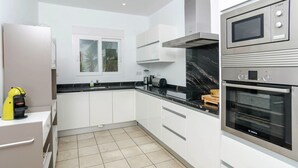 Et moderne køkken med hvide skabe, en Bosch ovn, en mikrobølgeovn og en gul enhed på bordpladen.