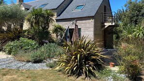 Une maison avec un toit en pente, une cheminée en pierre et un balcon en bois.