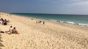Une vaste plage de sable où l’on voit des gens se promener et s’asseoir.