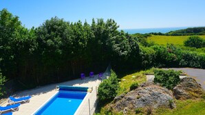 A swimming pool with lounge chairs and a view of the sea. - MANOR ON COAST WITH SEA VIEWS, TENNIS COURT, BIG GAMES ROOM + BAR, GARDENS (Ventnor)