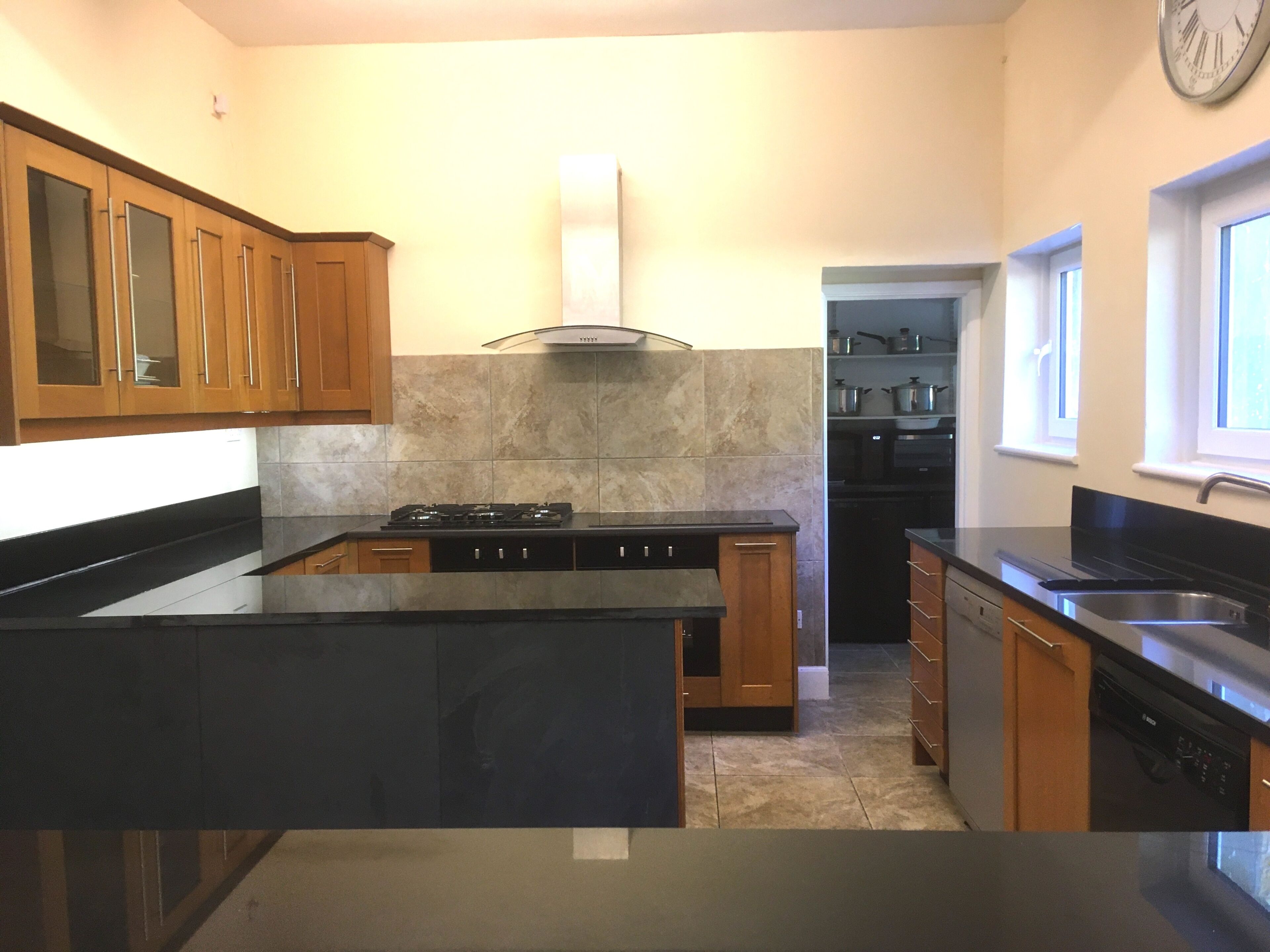 A modern kitchen with wooden cabinets, a central island, a stove, and a dishwasher.