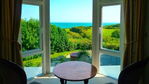 A room with a bay window overlooking a lush landscape and the sea. - MANOR ON COAST WITH SEA VIEWS, TENNIS COURT, BIG GAMES ROOM + BAR, GARDENS (Ventnor)