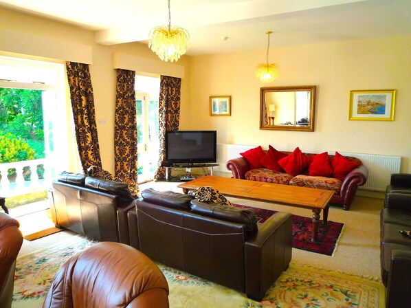 A living room with a sofa, a coffee table, a television, and a chandelier.