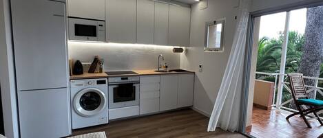 A modern kitchen with built-in appliances, a wooden countertop, and a view of the outdoors through a sliding glass door.