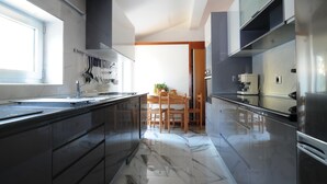 A modern kitchen with a marble countertop, stainless steel appliances, and a wooden dining table with chairs.