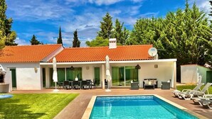A modern house with a swimming pool, outdoor seating, and a covered patio.