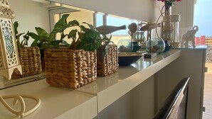 A kitchen counter with woven baskets containing plants, a decorative glass bowl, and a vase with flowers.