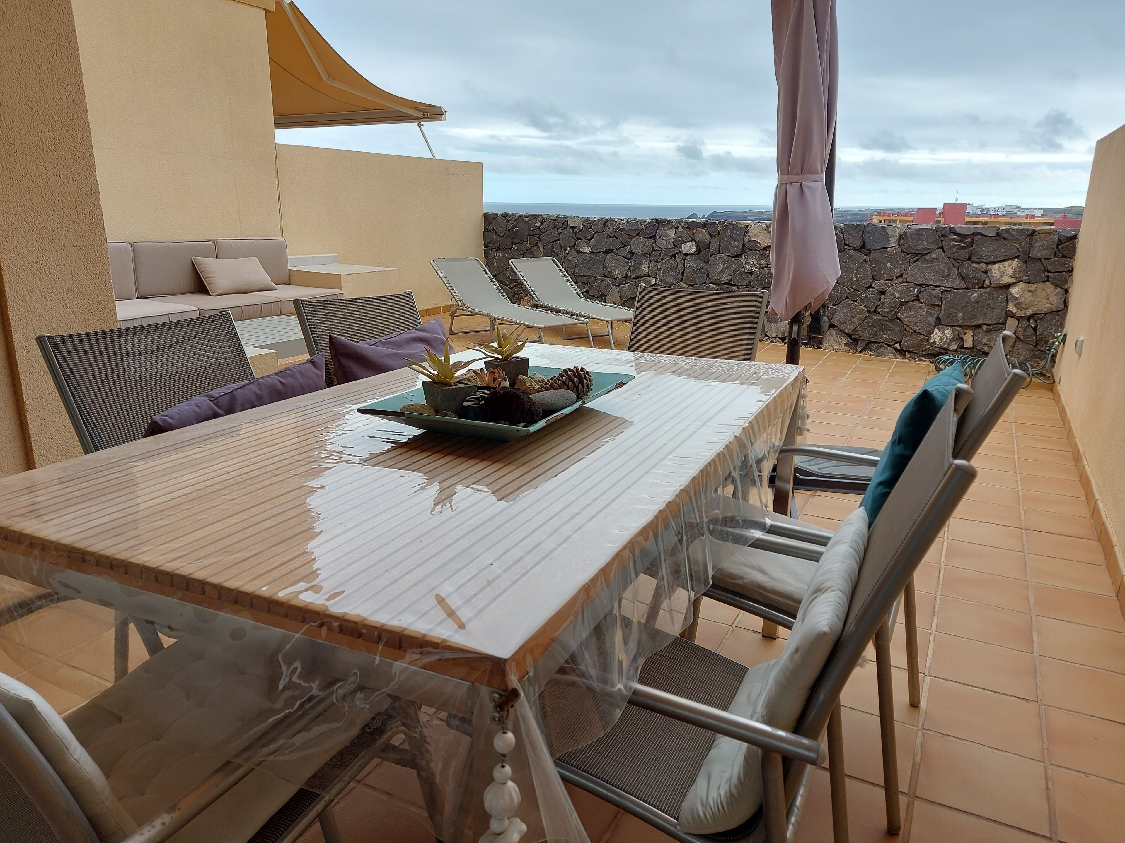 A patio with a table, chairs, and a stone wall.