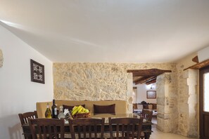 Un comedor con pared de piedra, muebles de madera y un arco de piedra que conduce a otra habitación.