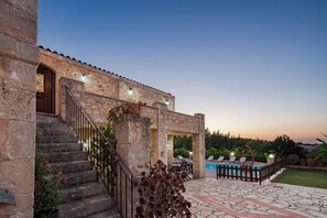 A stone building with a pool, outdoor seating, and a staircase leading to the entrance. - Family Getaway in Historic Village | Fenced Pool & Lush Gardens (Rethymno)