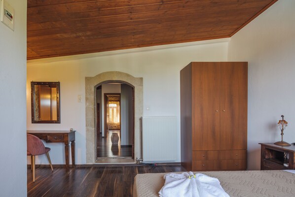 A bedroom with a wooden ceiling, a bed with a white blanket, a wooden wardrobe, and a desk with a chair. - Family Getaway in Historic Village | Fenced Pool & Lush Gardens (Rethymno)