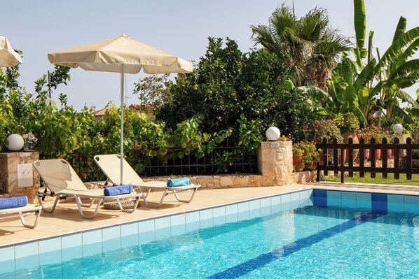 A pool area with lounge chairs, a canopy, and lush greenery.