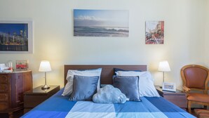 Ein Hotelzimmer mit einem Bett, zwei Nachttischen, einem Sessel und Bildern an der Wand.