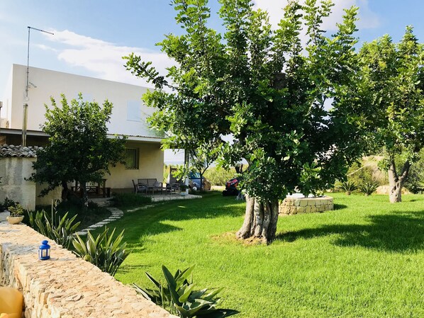 Un jardín bien cuidado con un muro de piedra, un banco y césped.