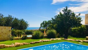 A rectangular swimming pool with clear blue water, surrounded by a well-maintained lawn and stone walls. - Single villa with private pool and lovely sea view (Cava D'aliga)