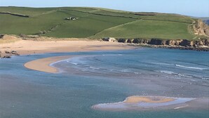A coastal landscape with rolling hills, a sandy beach, and a clear blue sky. - Luxury Apartment, Magnificent Sea Views, Private Access to Beach, Bigbury-on-Sea (Bigbury on Sea)