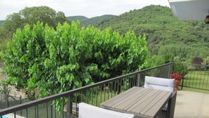 A balcony with a pool, wicker furniture, and a view of lush greenery.