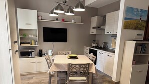 Una cocina moderna con una mesa de comedor, sillas, un microondas y un televisor de pantalla plana montado en la pared.