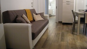 Un espacio de estar con un sofá, una mesa de centro y una mesa de comedor con sillas.
