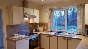 A modern kitchen with a built-in oven, a sink, and a window with curtains.